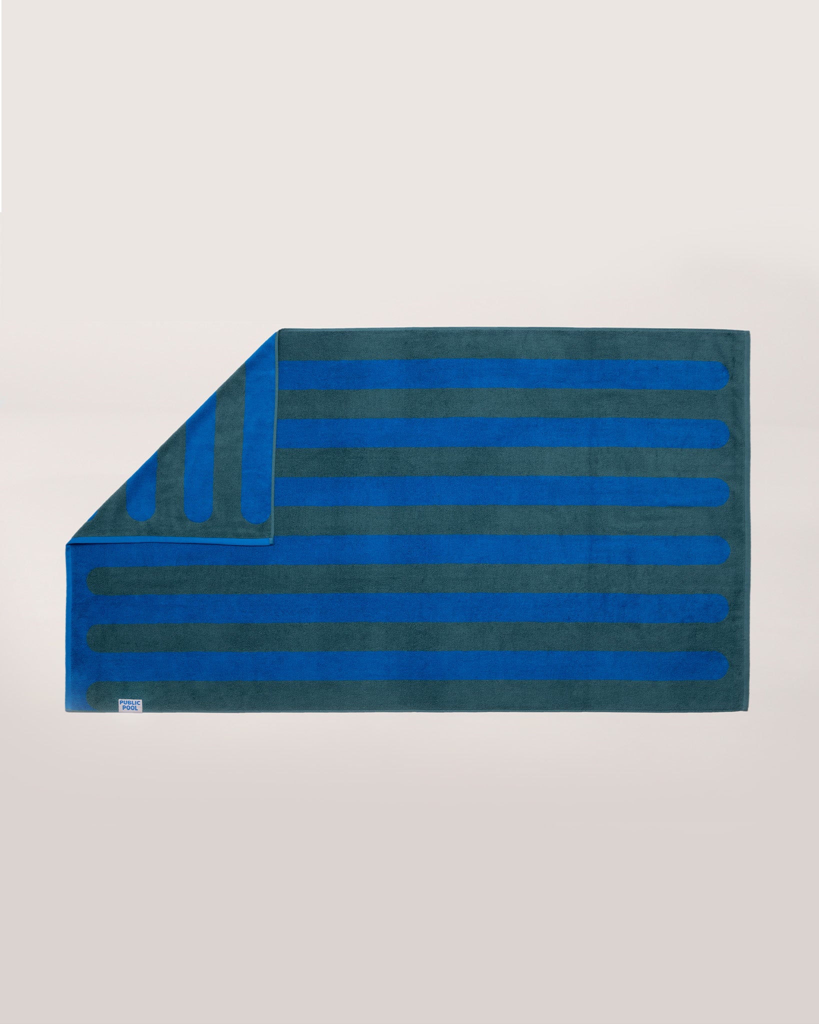 A blue and green striped pool towel laying on a cream background. 