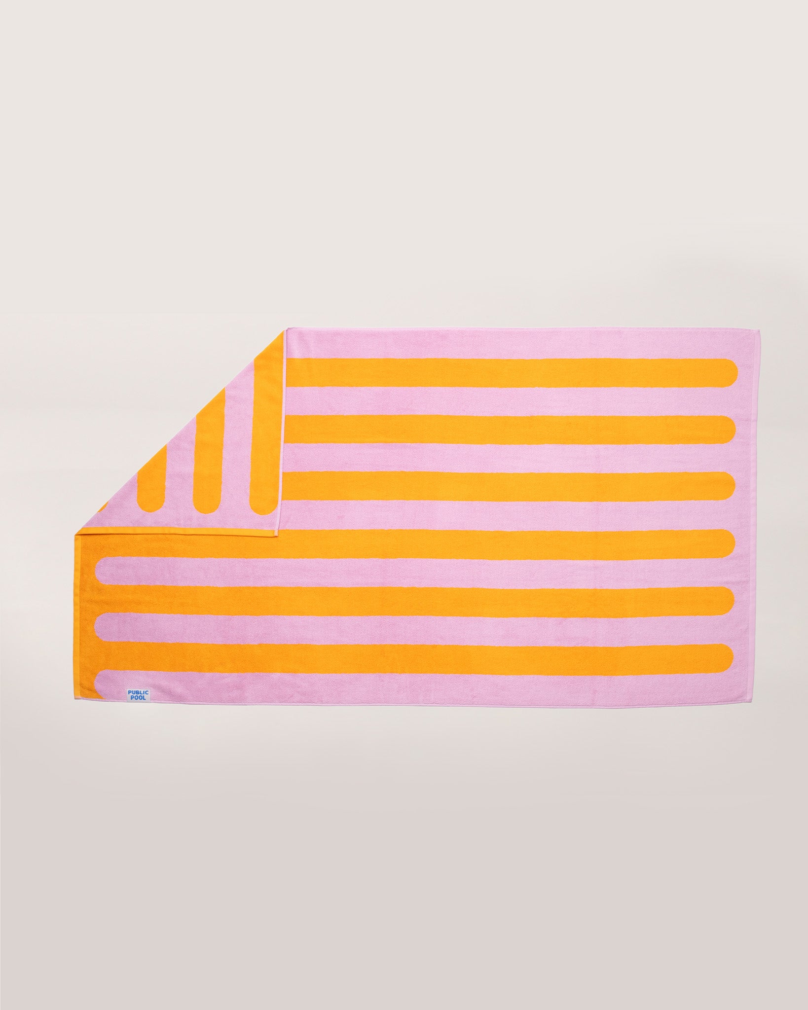 A light pink and orange striped pool towel laying on a cream background. 