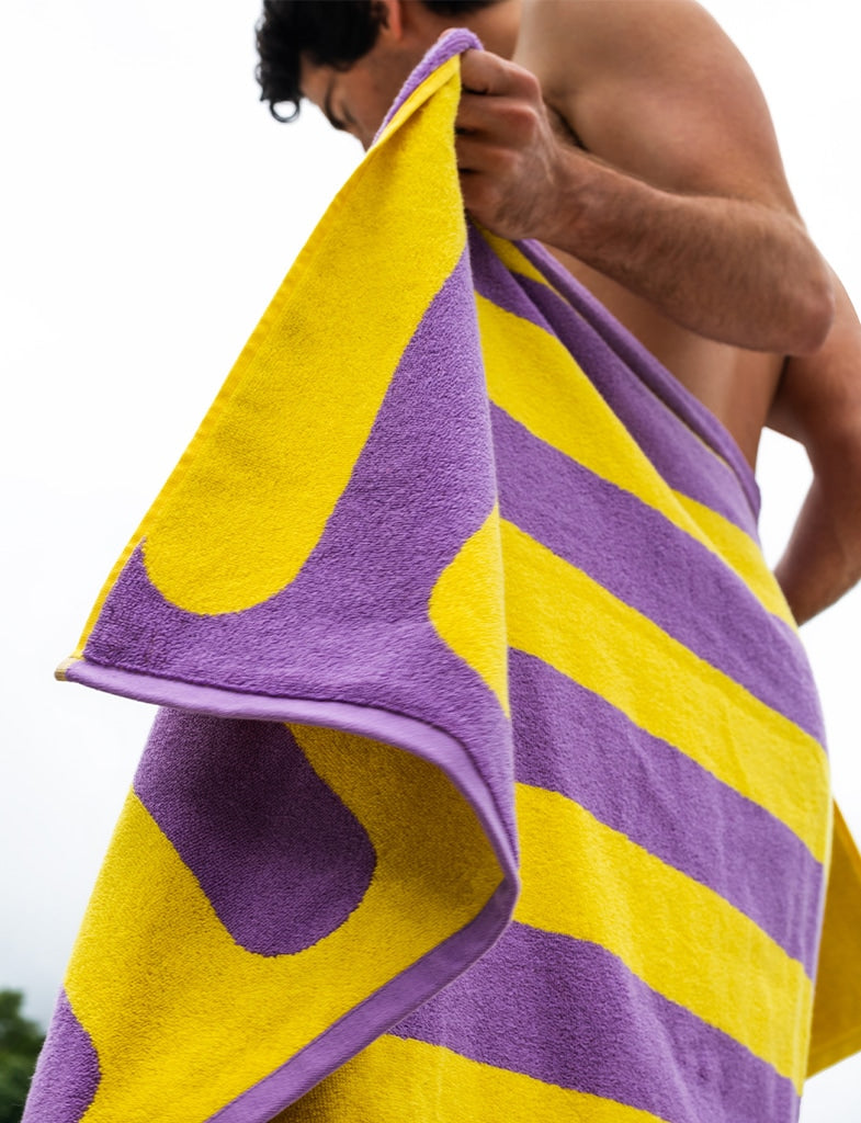 A man drying off his back with a towel. 