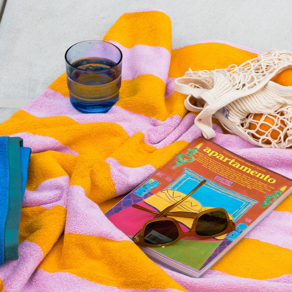 A glass, book, and towel on concrete. 