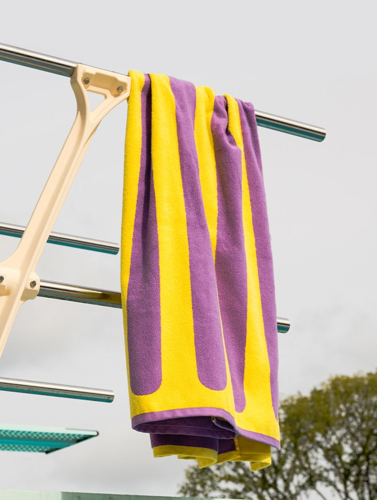A single towel hanging from the railing of a diving board.