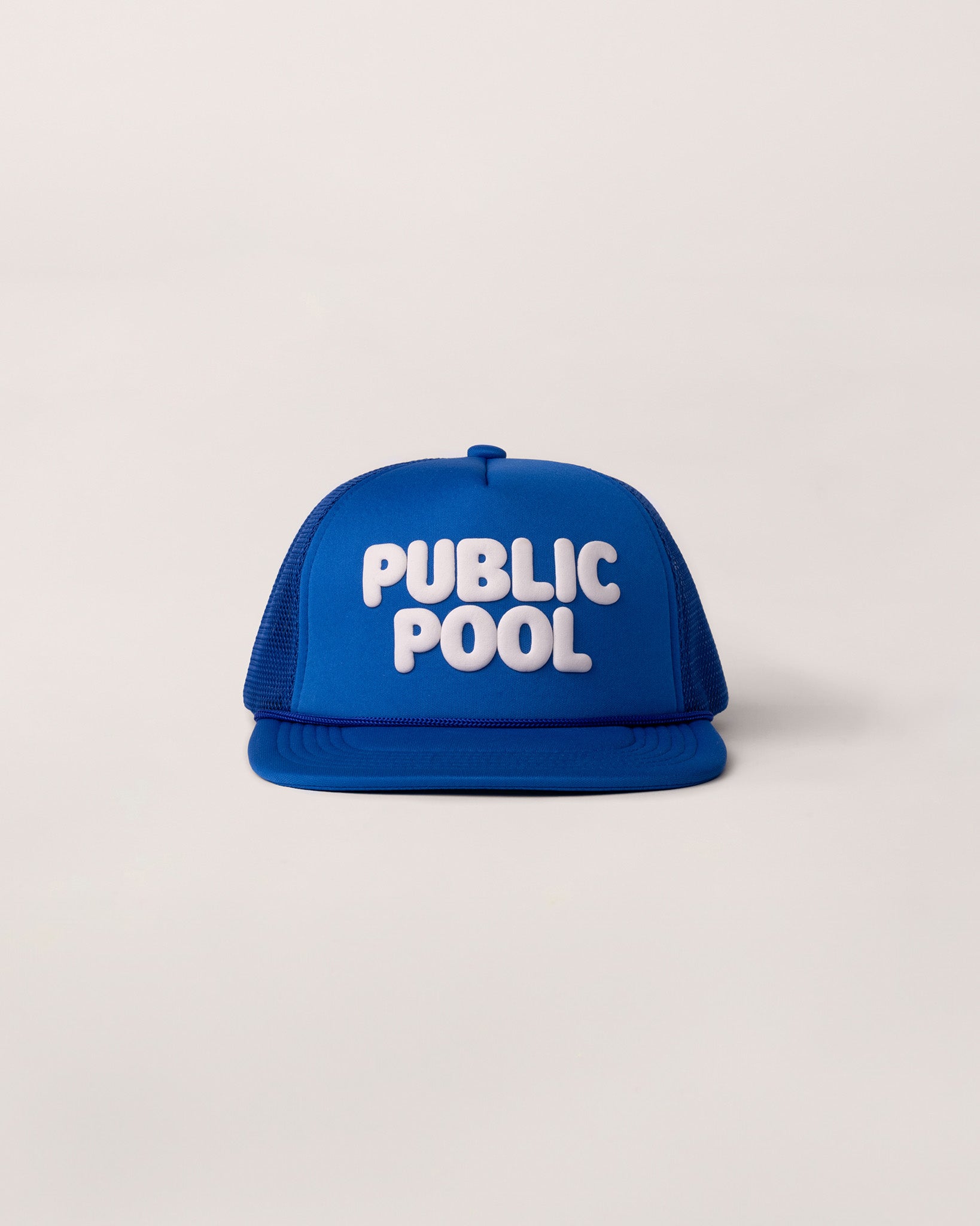 A blue trucker hat with a white Public Pool logo. 